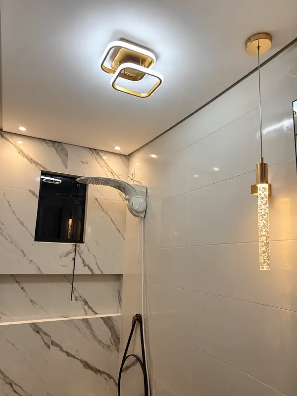 Banheiro com plafon dourado e pendente de cristal
